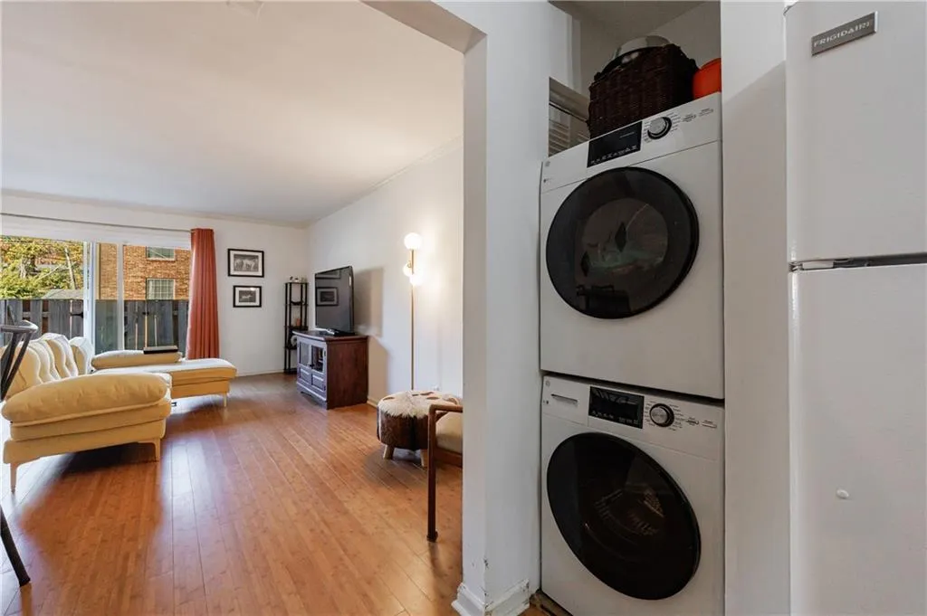 Laundry room with light wood-type flooring, stacked washing machine and dryer, and ornamental molding
