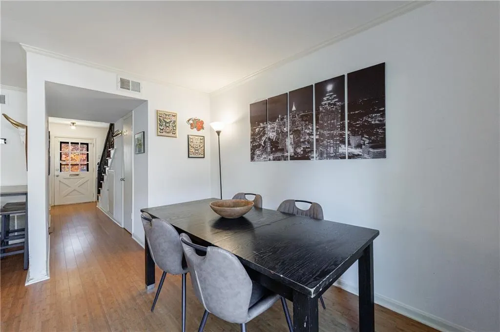 Dining area with crown molding, wood finished floors, and stairway