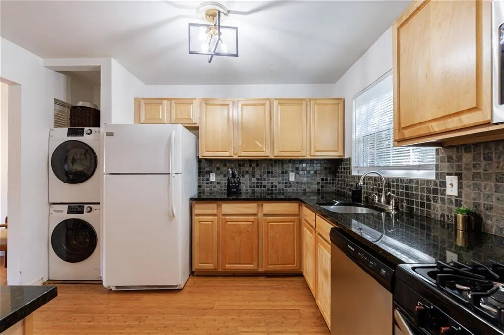 Kitchen with freestanding refrigerator, light wood-style floors, backsplash, dishwasher, and black gas stove