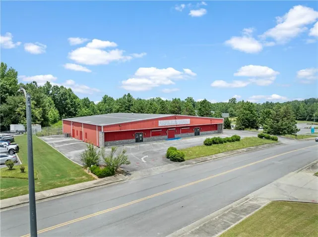Commercial building featuring a red metal facade with stone accents, a gray metal roof, and multiple entry points
