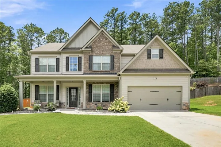 Two-story residence featuring a brick and siding facade, a covered front porch, and a two-car garage