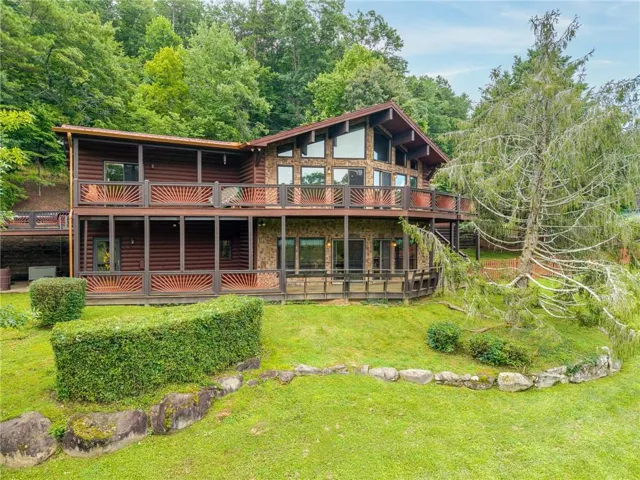 Multi-level log cabin-style exterior featuring extensive stone accents and a prominent A-frame roofline
