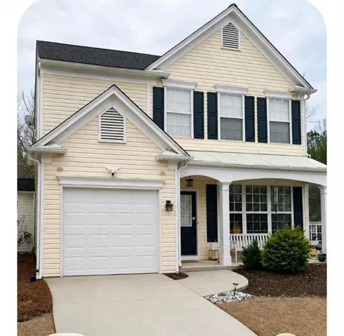 Two-story residence featuring light-colored siding, contrasting dark shutters, and a covered front porch with white columns