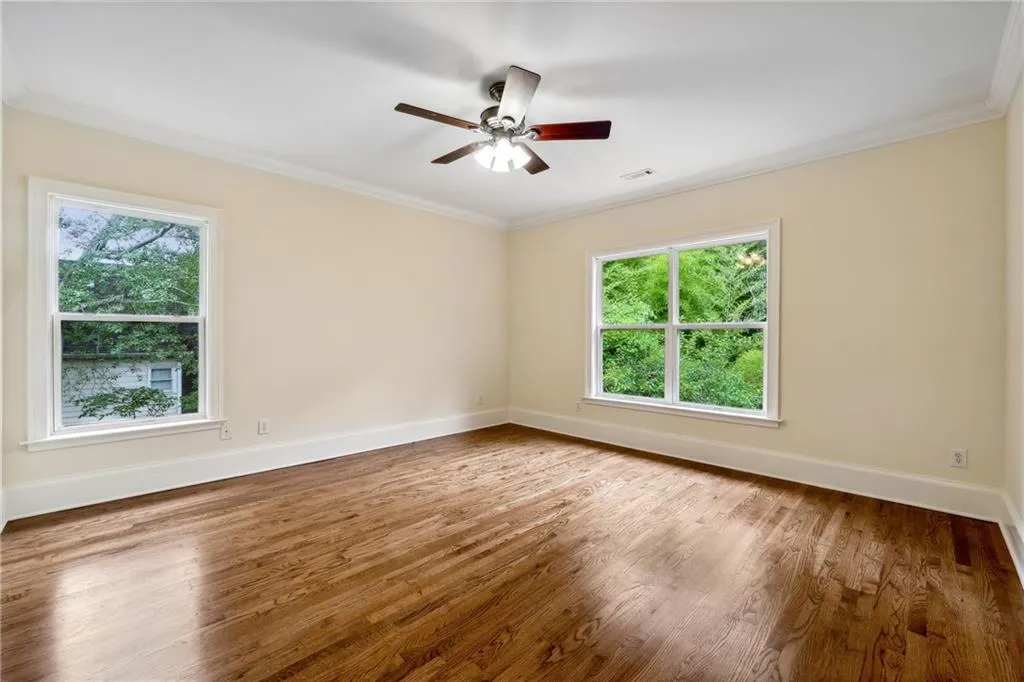 Empty room with wood-type flooring, ornamental molding, and ceiling fan