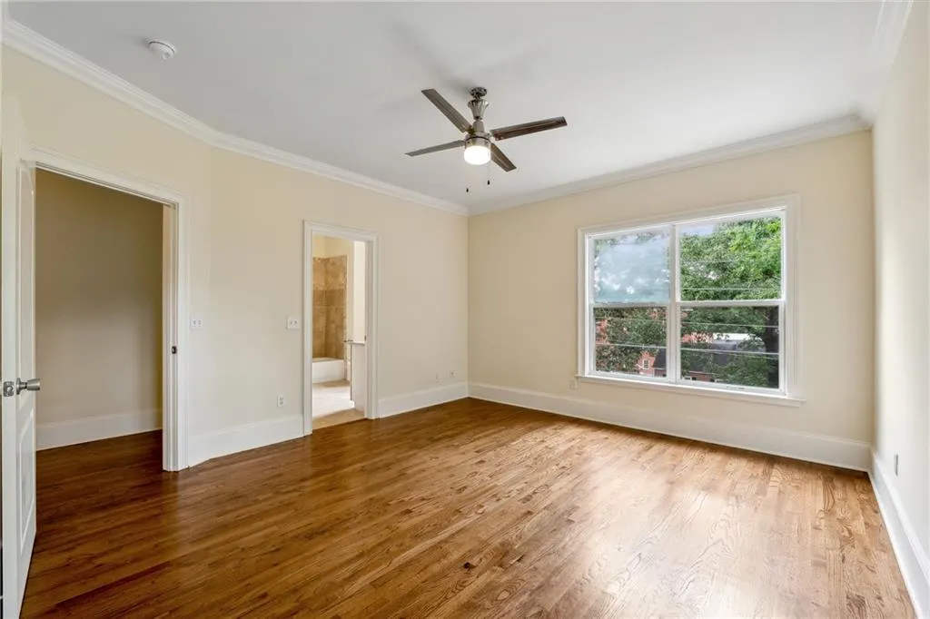 Spare room with wood-type flooring, ceiling fan, and crown molding