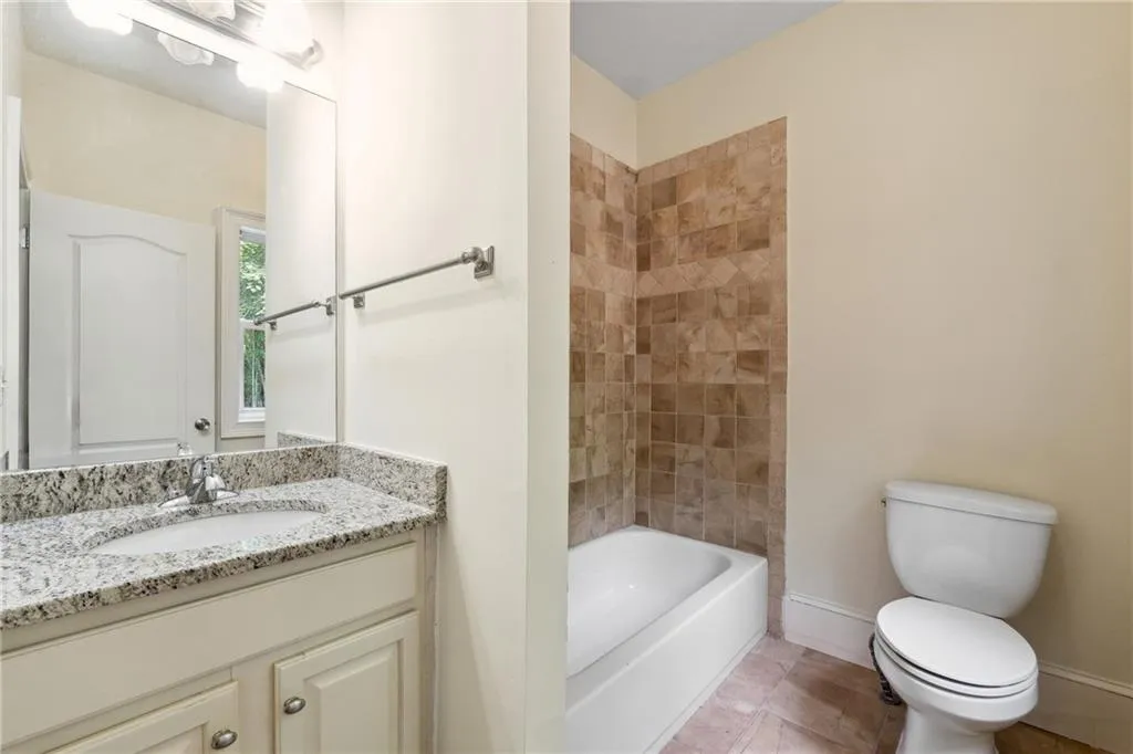 Full bathroom featuring vanity, toilet, tile patterned floors, and tiled shower / bath