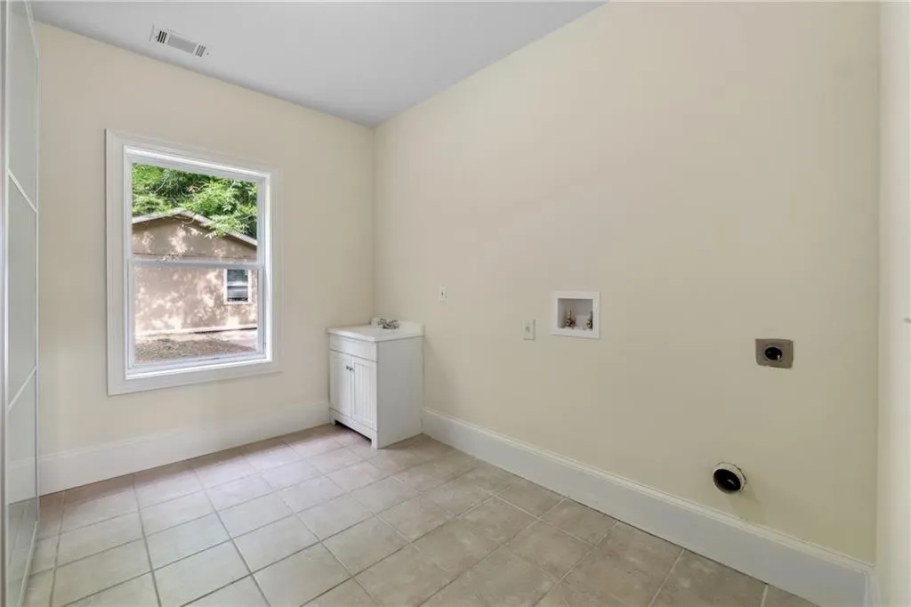 Laundry area with sink, light tile patterned floors, electric dryer hookup, and washer hookup