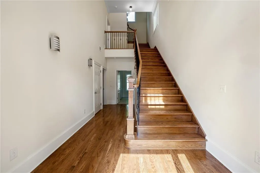 Staircase with hardwood / wood-style floors and a high ceiling