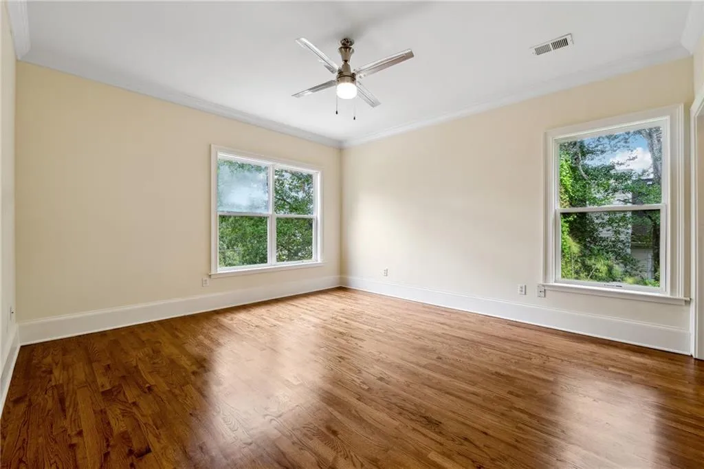 Spare room with a healthy amount of sunlight, hardwood / wood-style flooring, and ceiling fan