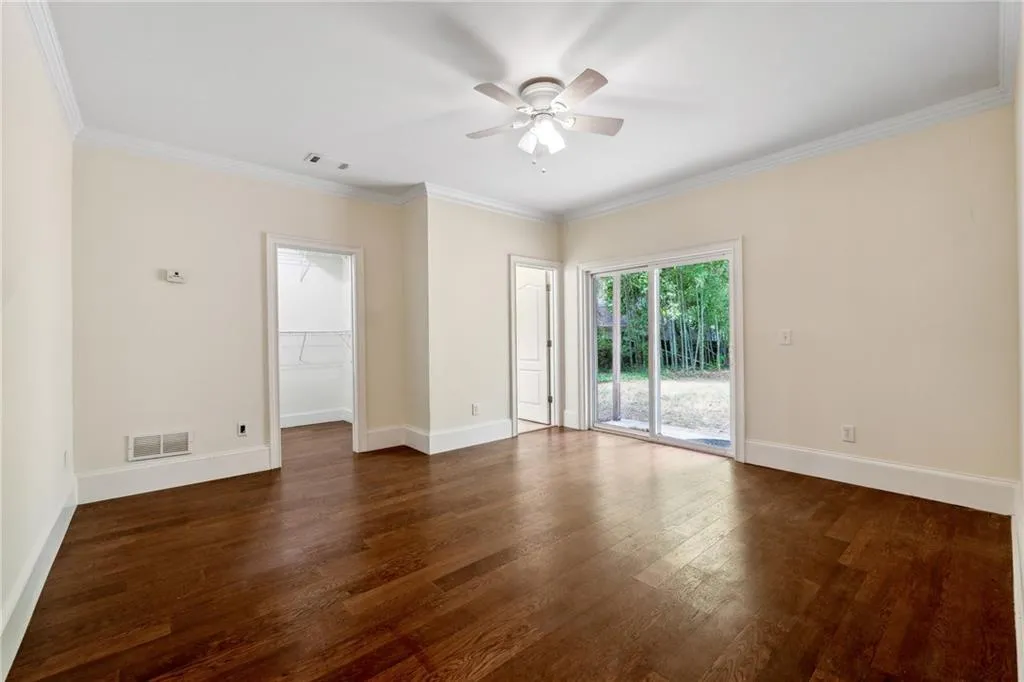Unfurnished room featuring ceiling fan, crown molding, and dark hardwood / wood-style flooring
