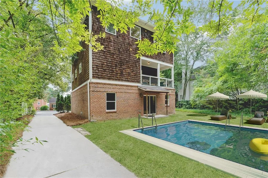 Rear view of house with a balcony and a lawn