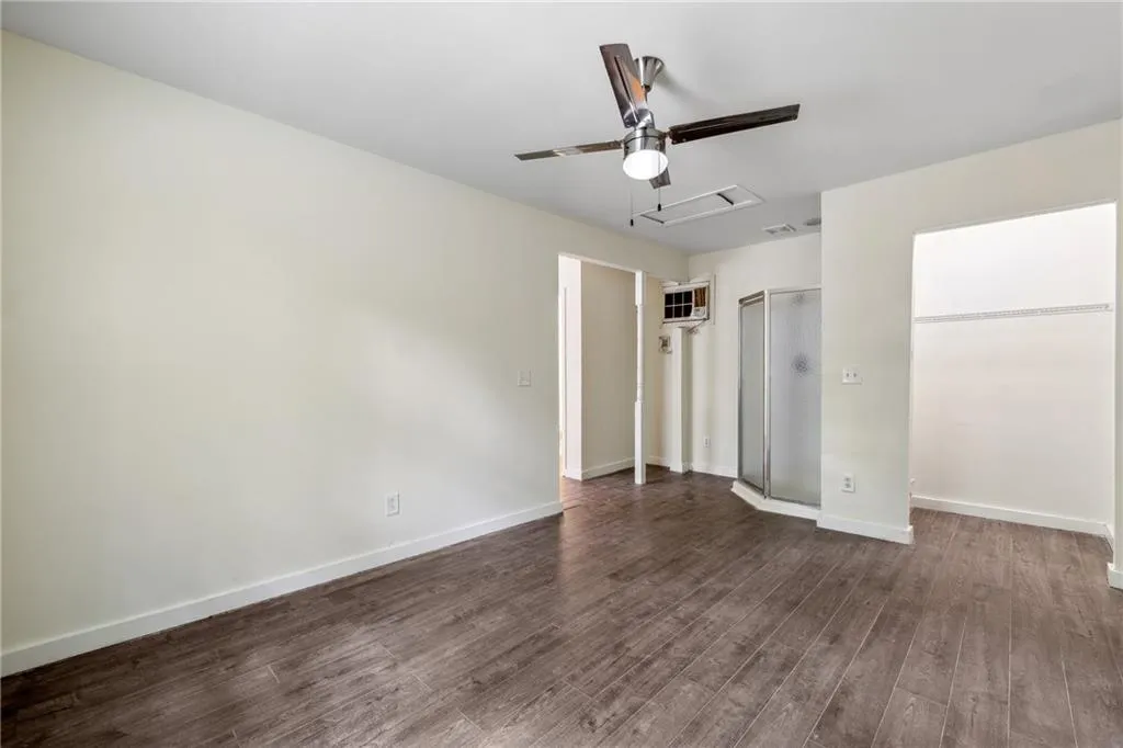 Unfurnished bedroom featuring ceiling fan and dark wood-type flooring