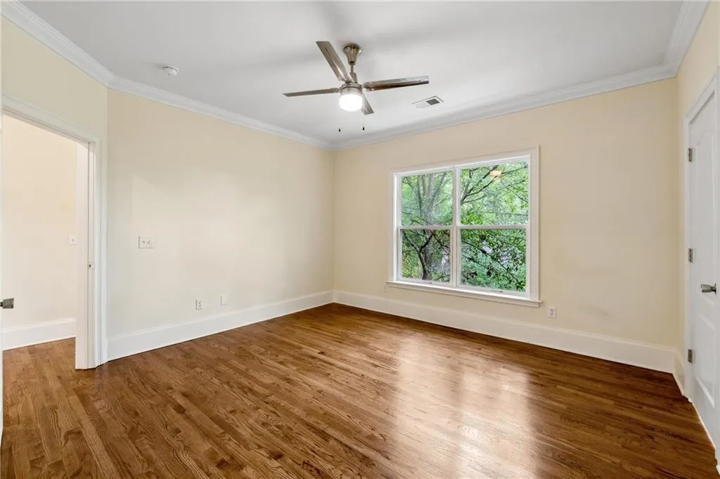 Spare room with dark wood-type flooring, ornamental molding, and ceiling fan