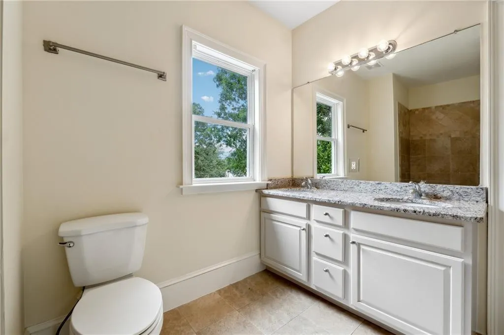 Bathroom featuring double vanity, tile patterned flooring, and toilet