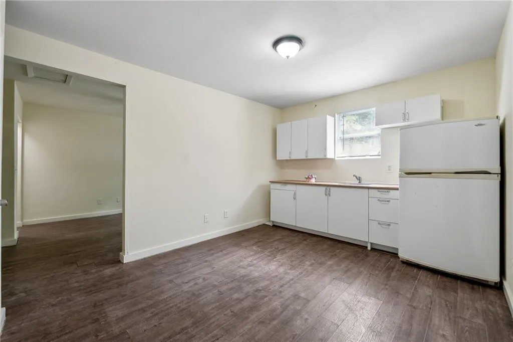Kitchen featuring sink, wood-type flooring, white refrigerator, and white cabinets