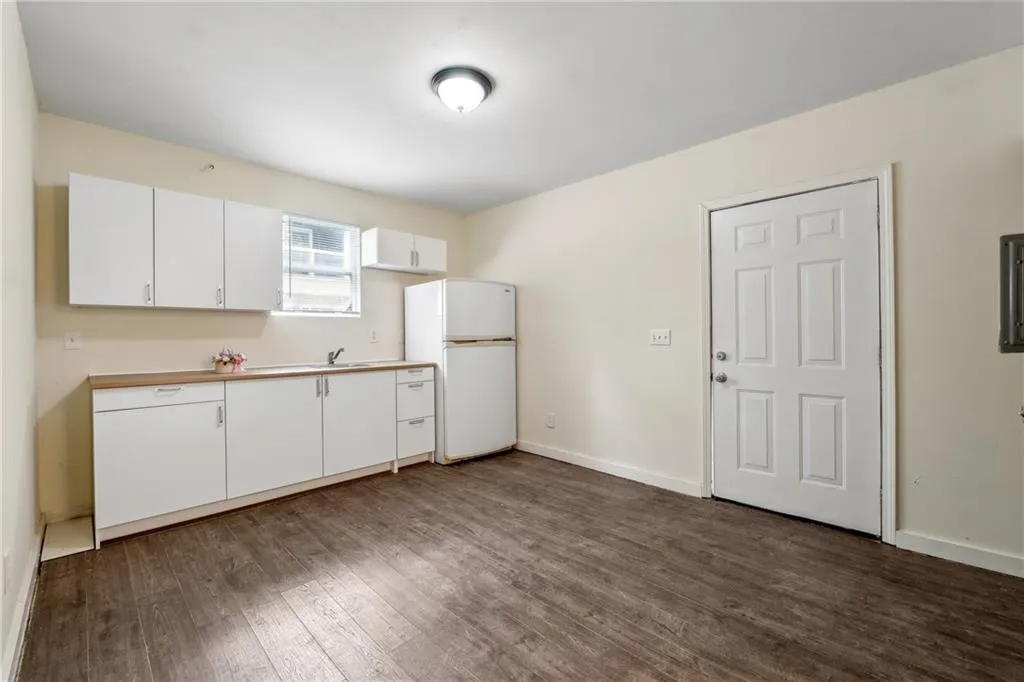 Kitchen with white cabinets, wood-type flooring, white refrigerator, and sink