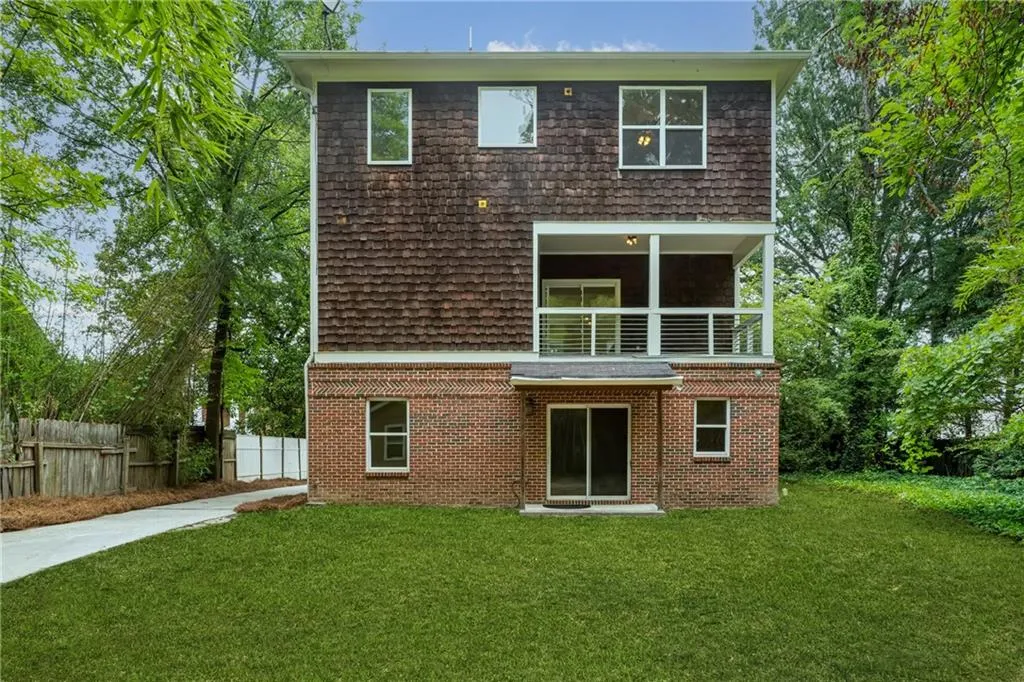 Back of property featuring a balcony and a lawn