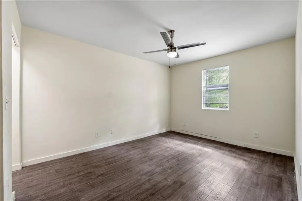Unfurnished room with dark wood-type flooring and ceiling fan