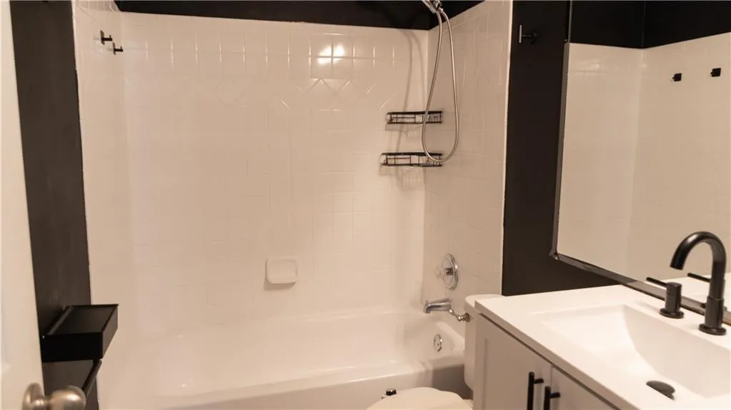 Full bathroom with vanity, tiled shower / bath combo, and toilet