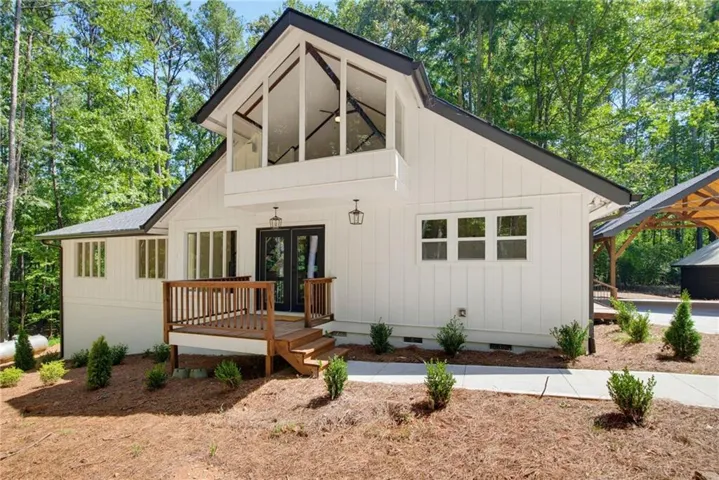 Modern farmhouse design featuring a steeply pitched gable roof with decorative cross-bracing, white vertical siding, and black trim accents