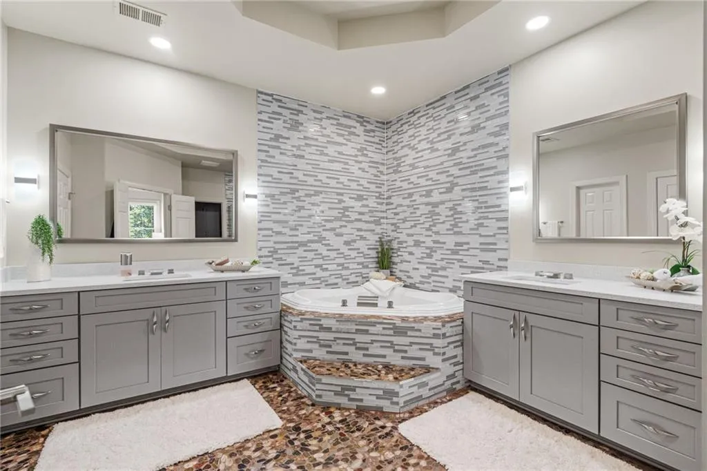 Renovated primary bath with new vanities, tile, fixtures and lighting. Walk in shower too.