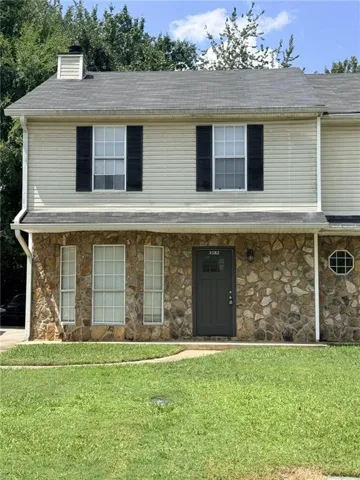 Stone veneer facade with a dark entry door and octagonal window