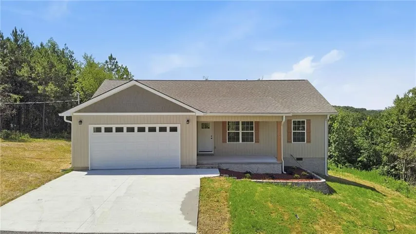 Contemporary ranch-style home featuring a two-car garage with panel windows, a concrete driveway, and a covered front porch