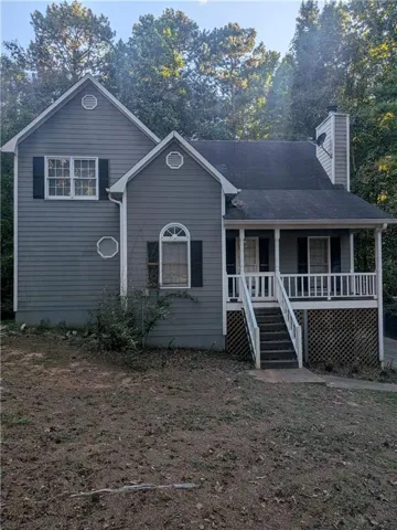 Gray siding exterior with a pitched roof, front porch with white railing, and decorative arched window