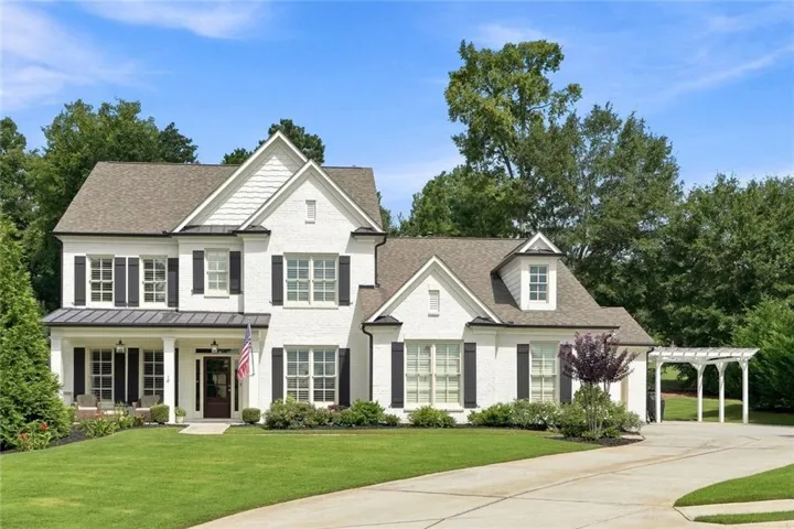 Elegant Colonial-style residence showcasing a cream exterior with dark shutters, multi-pane windows, and a prominent front-facing gable