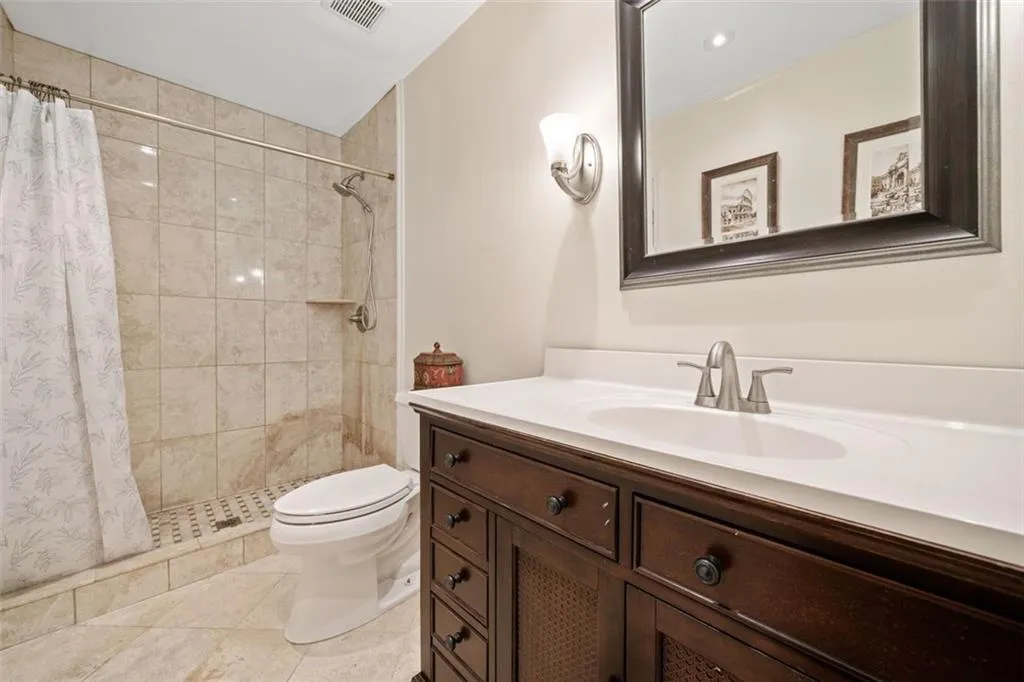 Bathroom featuring a shower with curtain, tile patterned flooring, vanity, and toilet