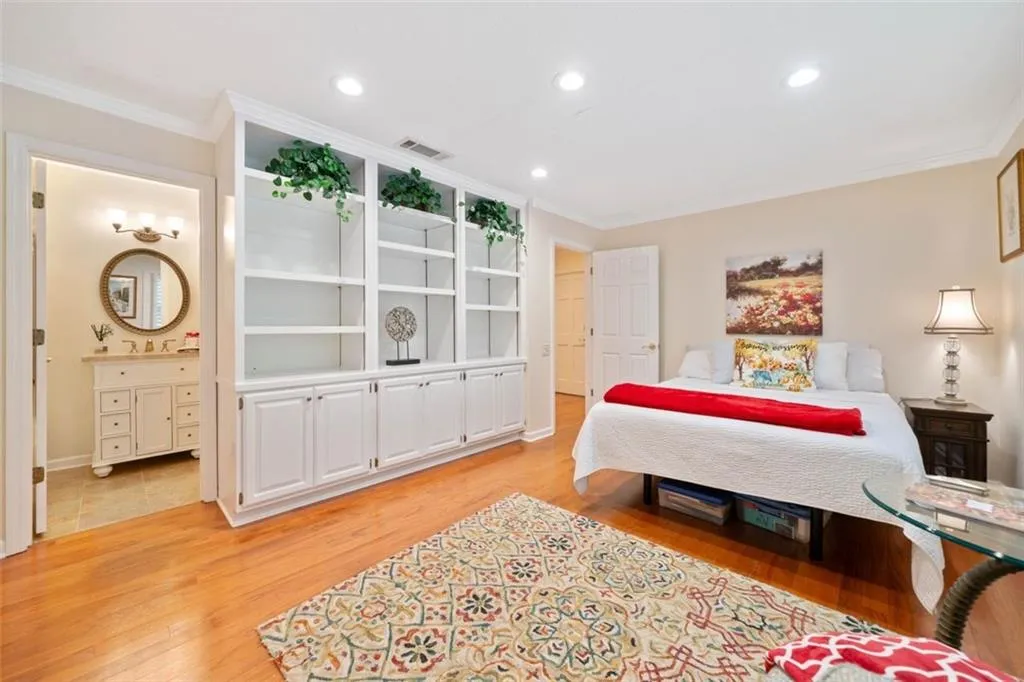 Primary Bedroom, Home Office or Guest Room on main with ensuite bathroom, crown molding, sink, and light wood-type flooring
