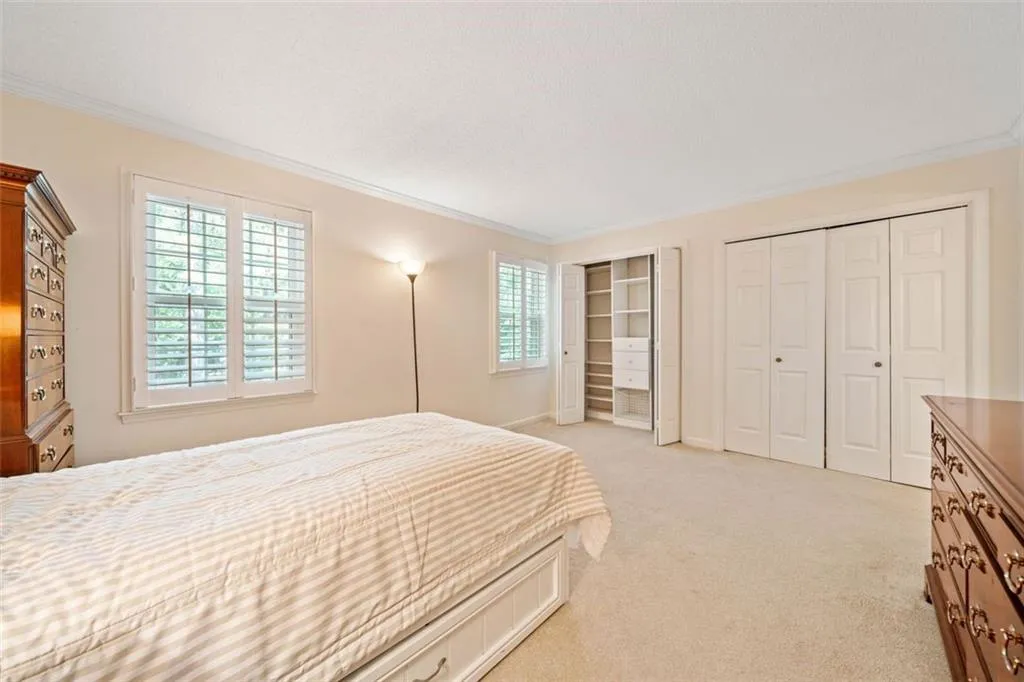 Carpeted bedroom with crown molding and multiple windows