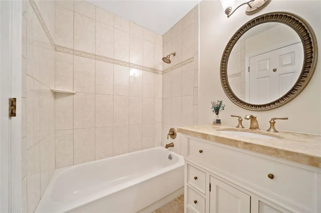 Bathroom with tiled shower / bath, tile patterned floors, and vanity