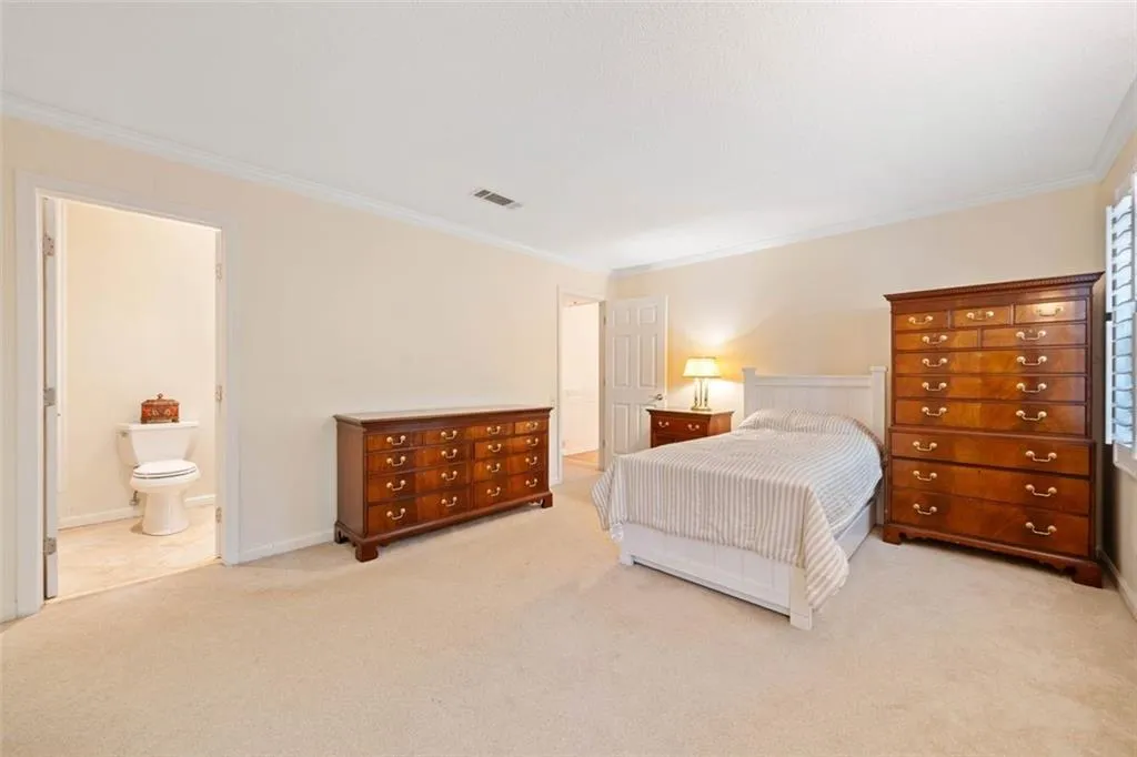 Carpeted bedroom with crown molding and ensuite bath