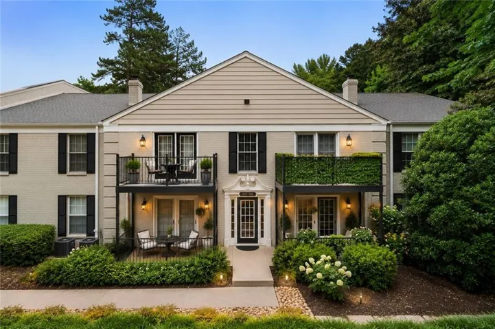 Brick and siding exterior with black shutters, multiple balconies, and mature landscaping