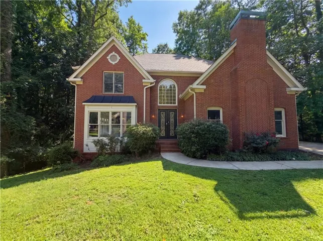 Traditional brick exterior featuring a prominent chimney with herringbone detailing, an arched entryway, and a bay window