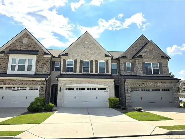 Brick exterior with shuttered windows, multiple garage doors, and front entry