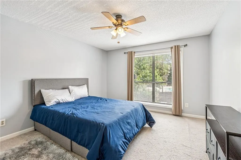Bedroom with carpet flooring, a textured ceiling, and ceiling fan