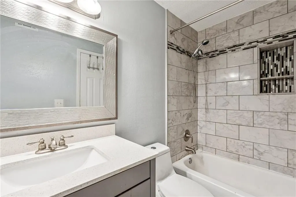 Bathroom with vanity, a textured ceiling,  shower combination, and a textured wall