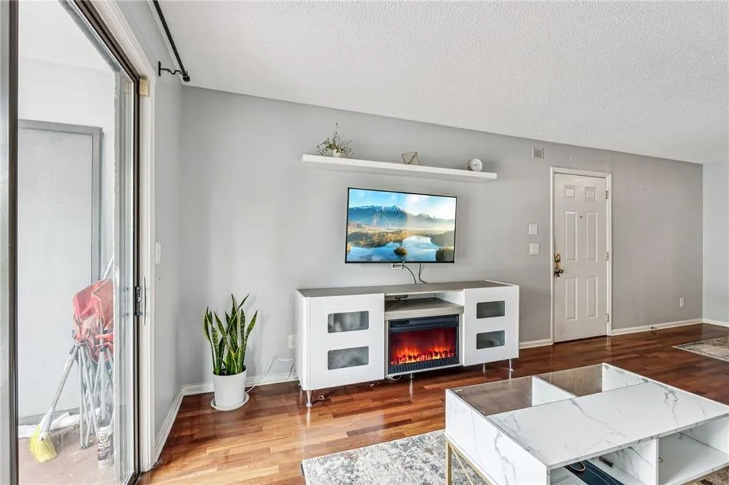 Living room featuring a textured ceiling, wood finished floors, and a glass covered fireplace