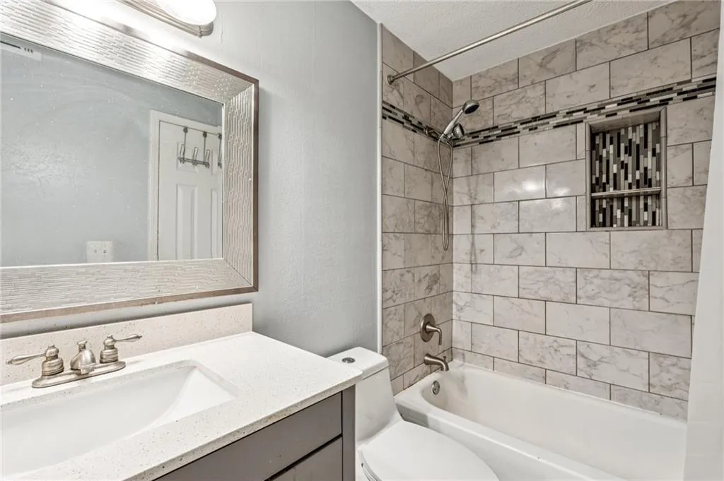 Full bathroom with a textured ceiling, a textured wall, vanity, and shower / bathtub combination
