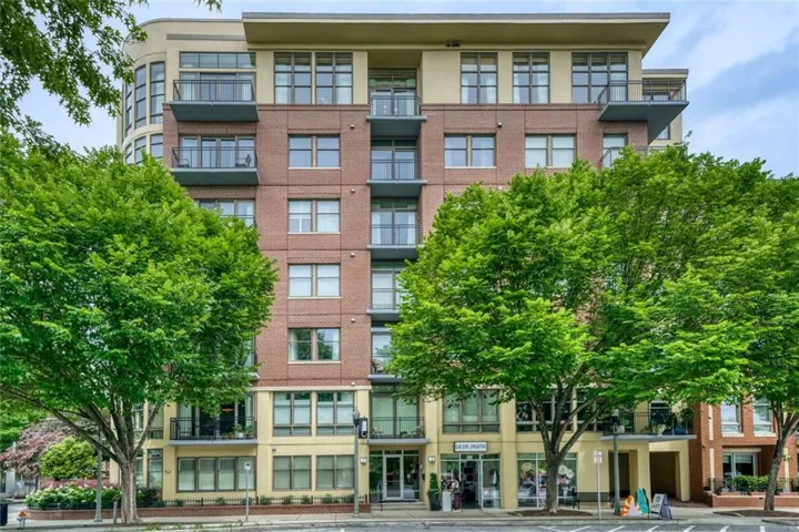 Multi-story building featuring a brick and stucco facade, private balconies, and ground-level retail spaces