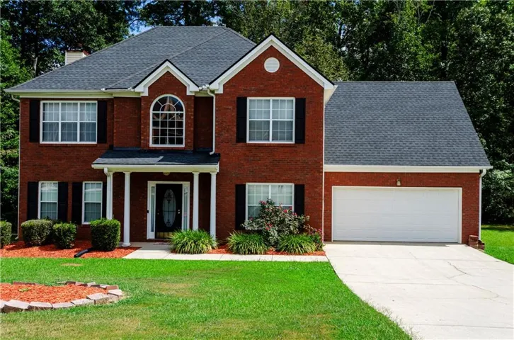 Brick exterior with white columned front porch, arched window, and attached garage