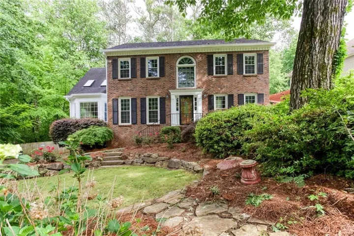 Brick exterior with black shutters and white trim, featuring a prominent arched window above the entry