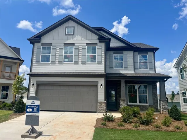 Contemporary exterior with mixed material siding, stone accents, covered entry, attached two-car garage, and established landscaping