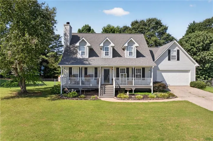 Traditional-style residence featuring light gray siding, dark shutters, and a covered front porch with white railing