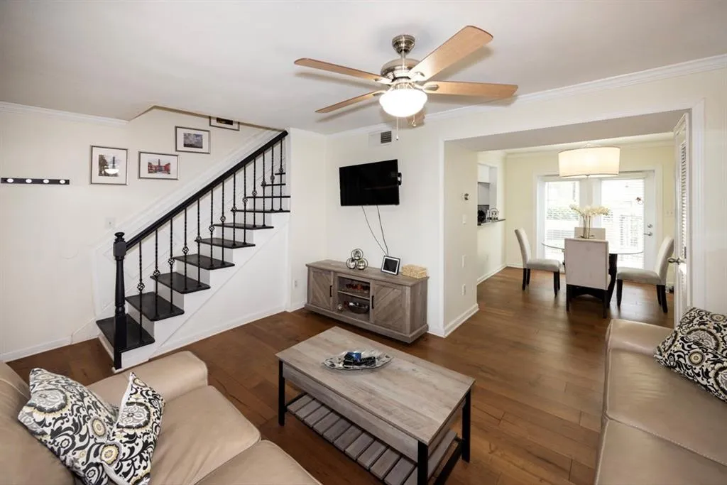 Living area featuring ornamental molding, stairway, ceiling fan, and dark wood-style flooring
