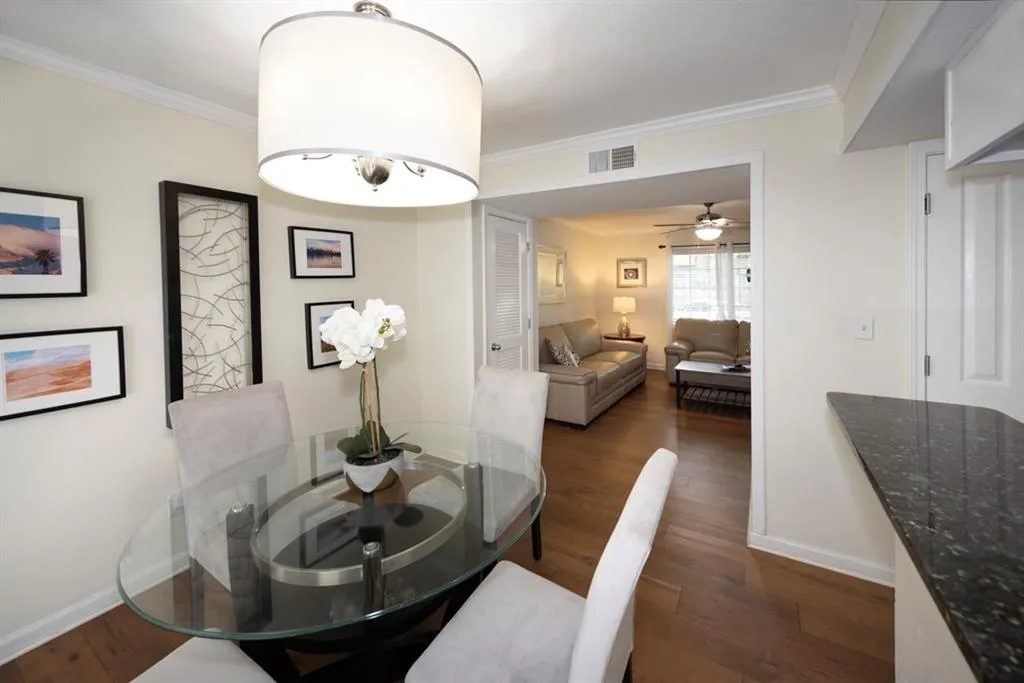 Dining space with dark wood-style flooring, crown molding, and ceiling fan