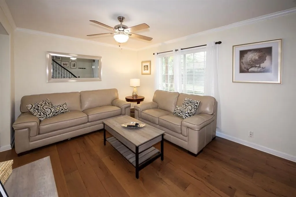 Living room featuring hardwood / wood-style floors, crown molding, and ceiling fan