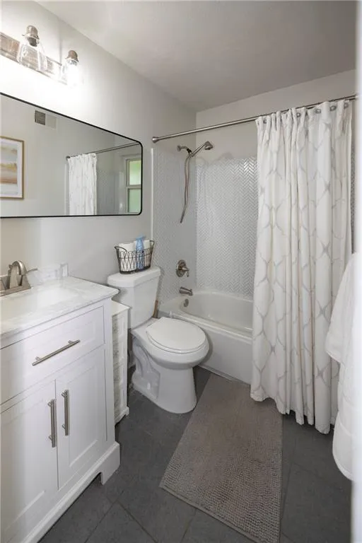 Bathroom featuring vanity, shower / bath combo with shower curtain, and tile patterned flooring
